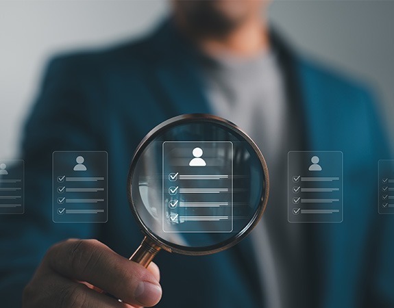 Man holding magnifying glass searching through candidates