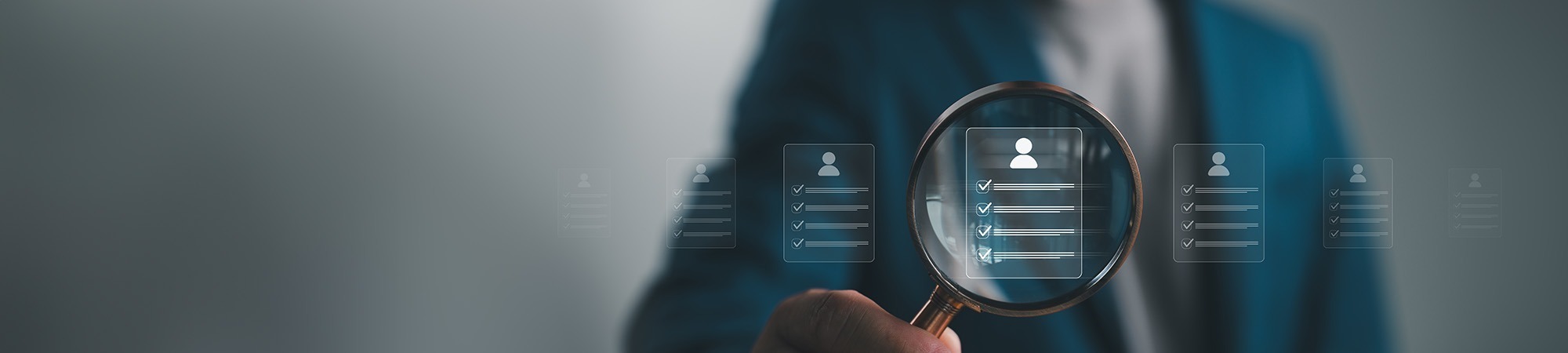 Man holding magnifying glass searching through candidates